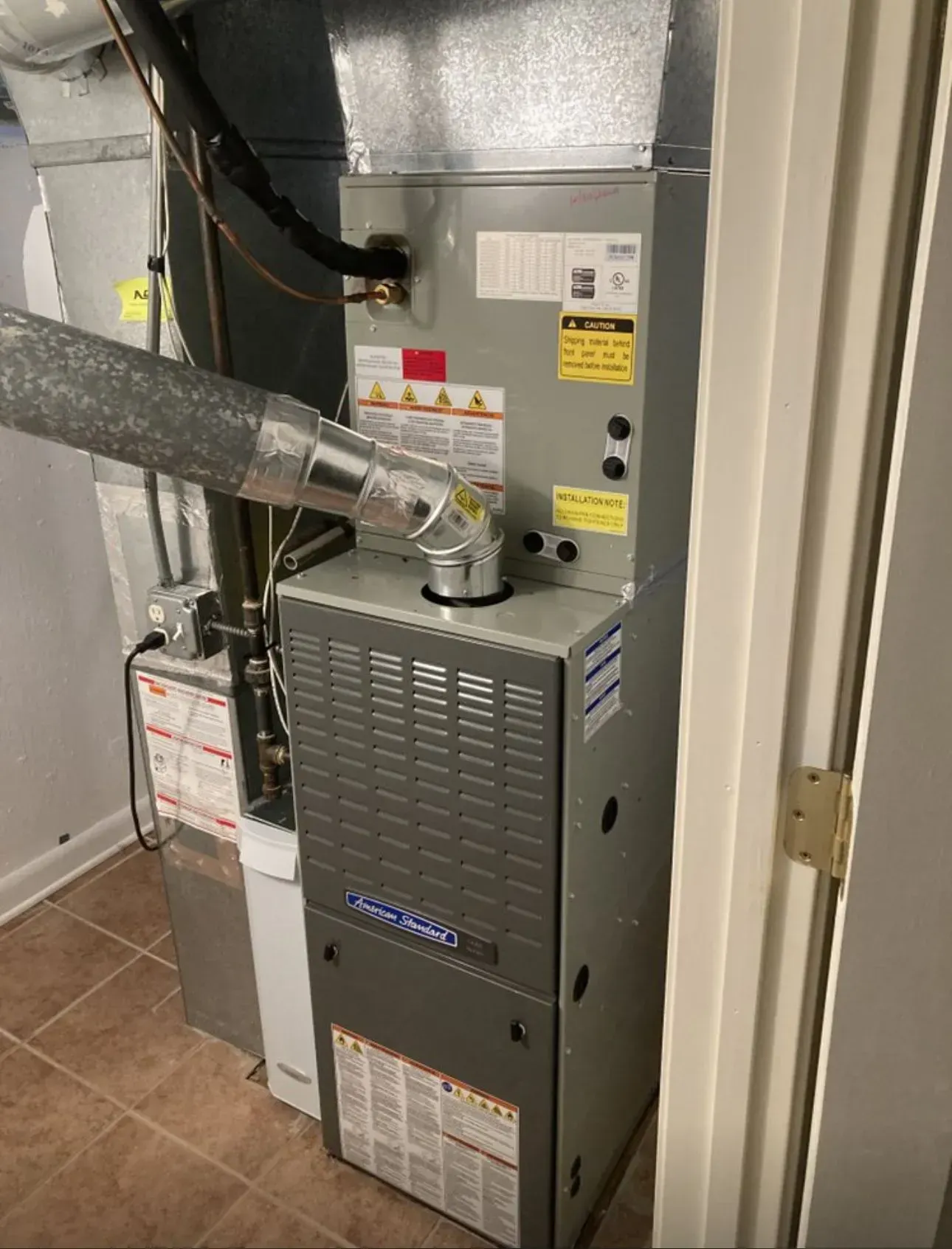 HVAC system, gray metal unit, connected to ductwork, inside utility closet.