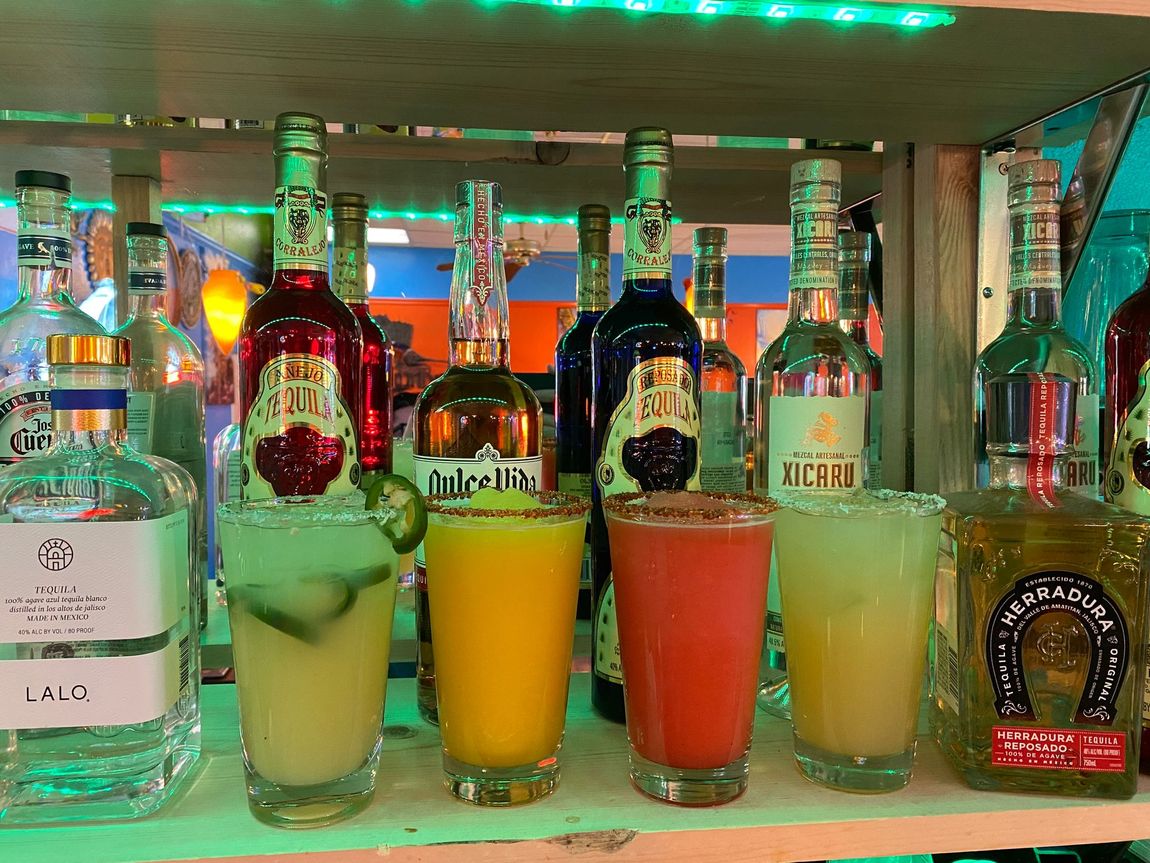A shelf filled with bottles and glasses of drinks.