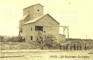 Vintage photo of the Bichler Quarry, 1910-20. Men gather near a large wooden industrial building.