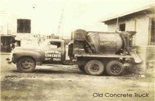 Vintage concrete mixer truck parked near a building.