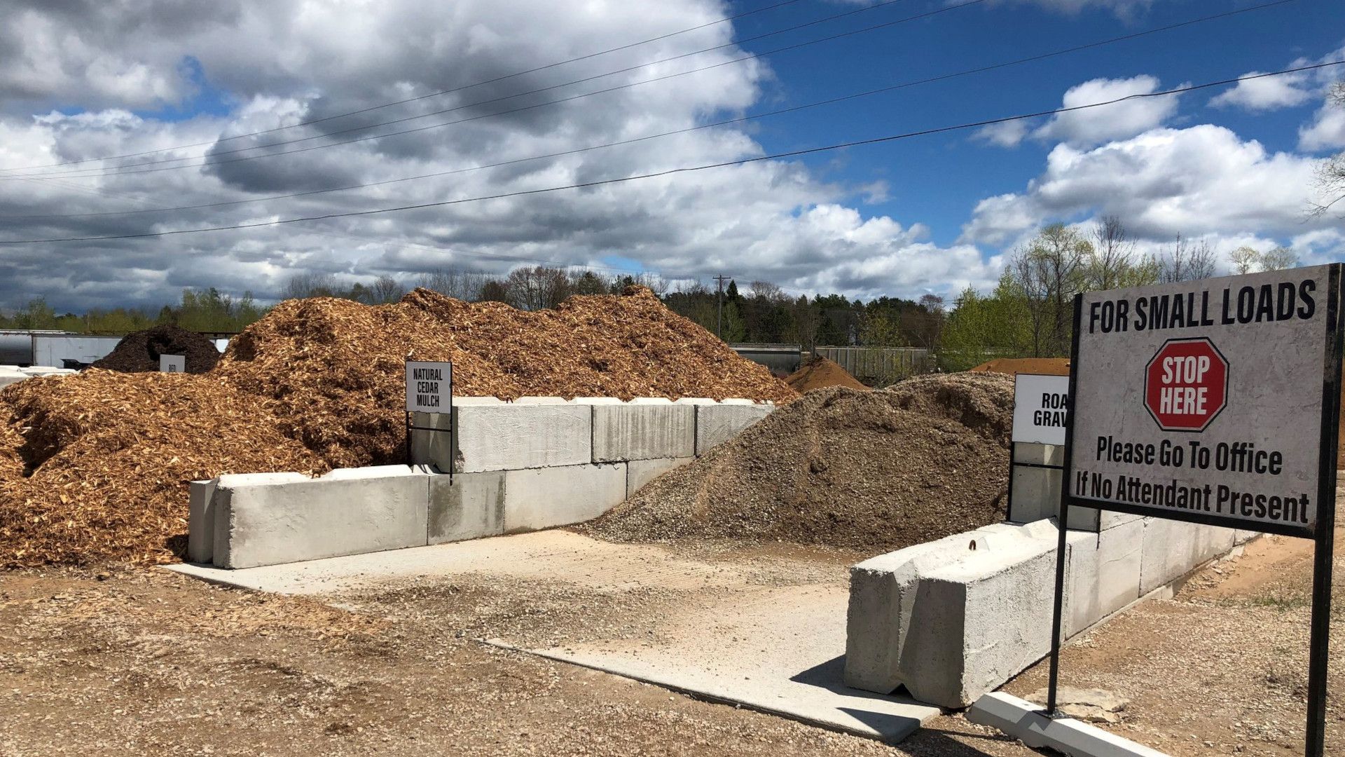 Wood chip piles at a disposal site with concrete barriers. Stop sign says, 