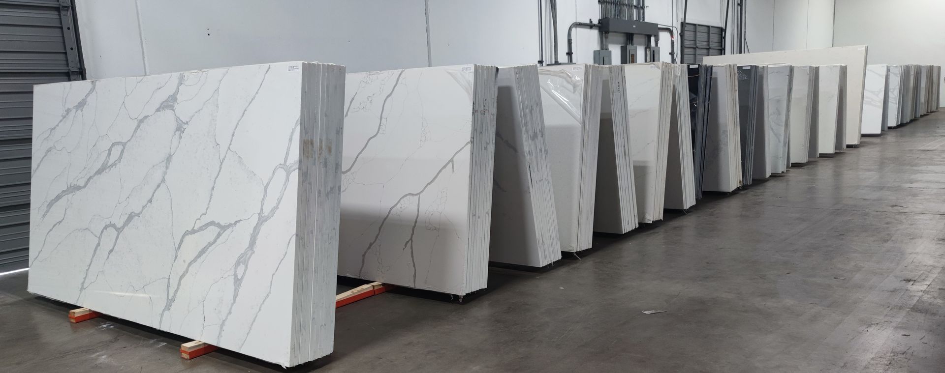 A row of white marble slabs are lined up in a warehouse.
