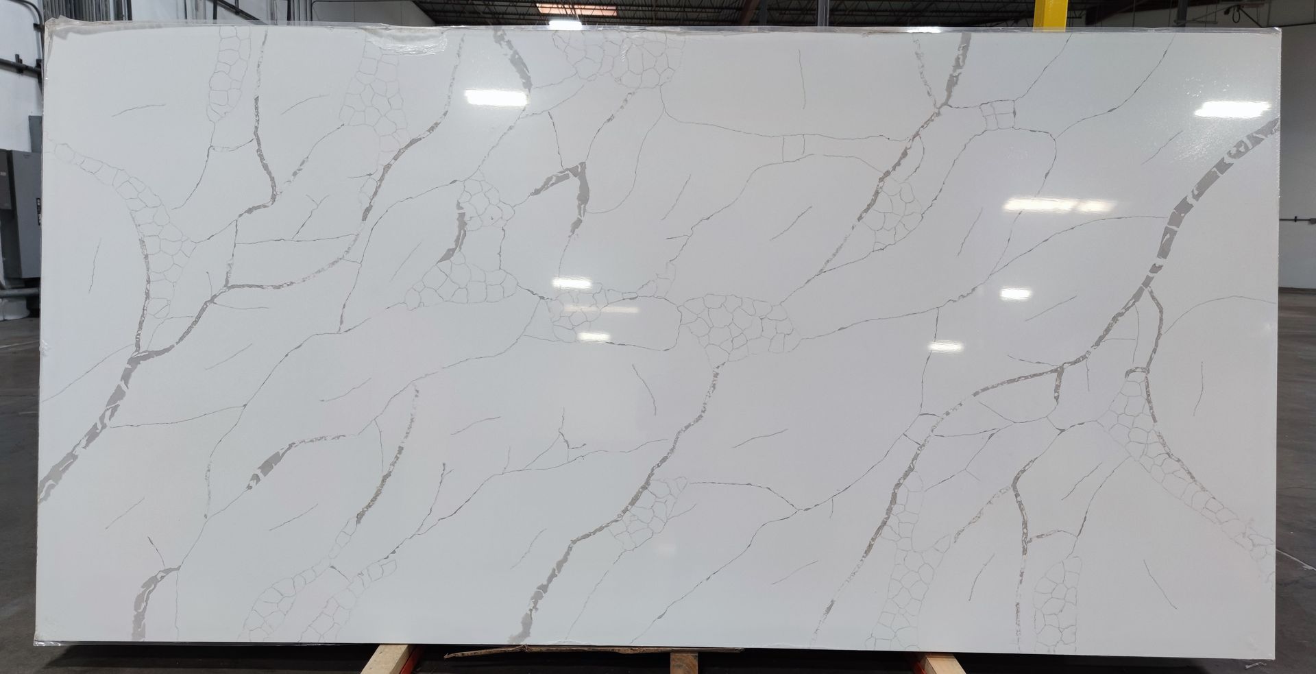 A large white granite slab is sitting on top of a wooden pallet in a warehouse.