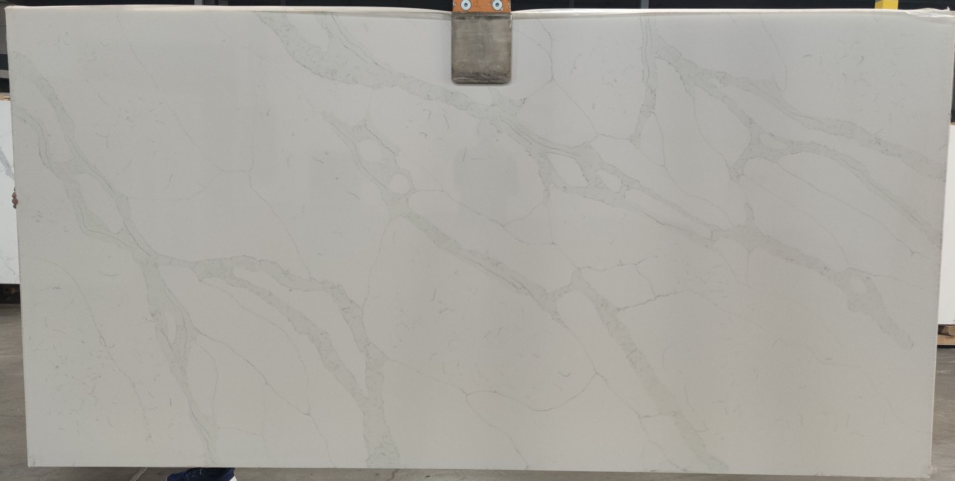 A person is holding a large white slab of marble.