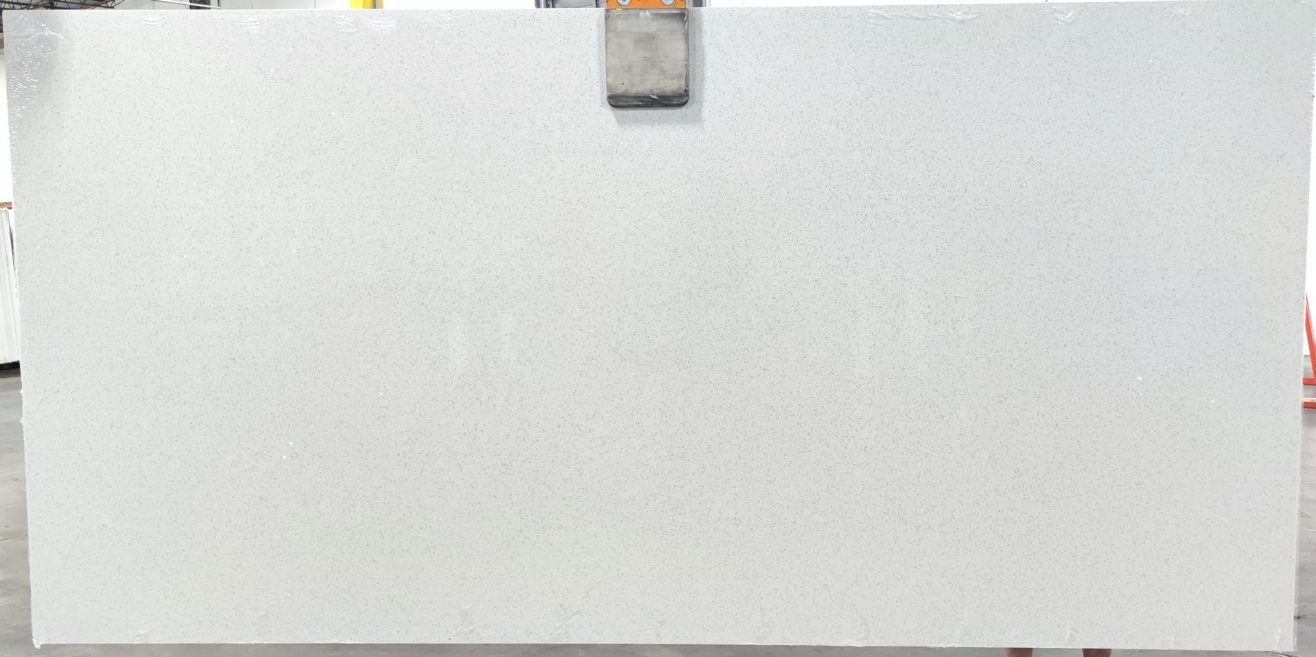 A large white slab of quartz is sitting on a concrete floor.