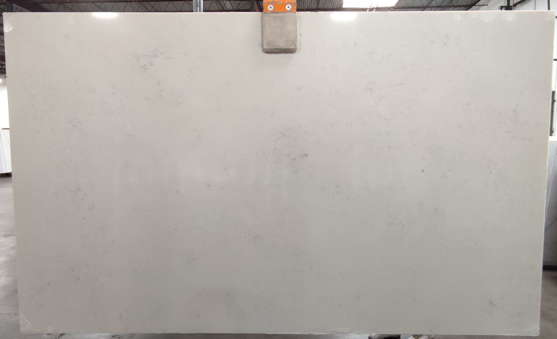 A large white granite slab is sitting on top of a concrete floor in a warehouse.