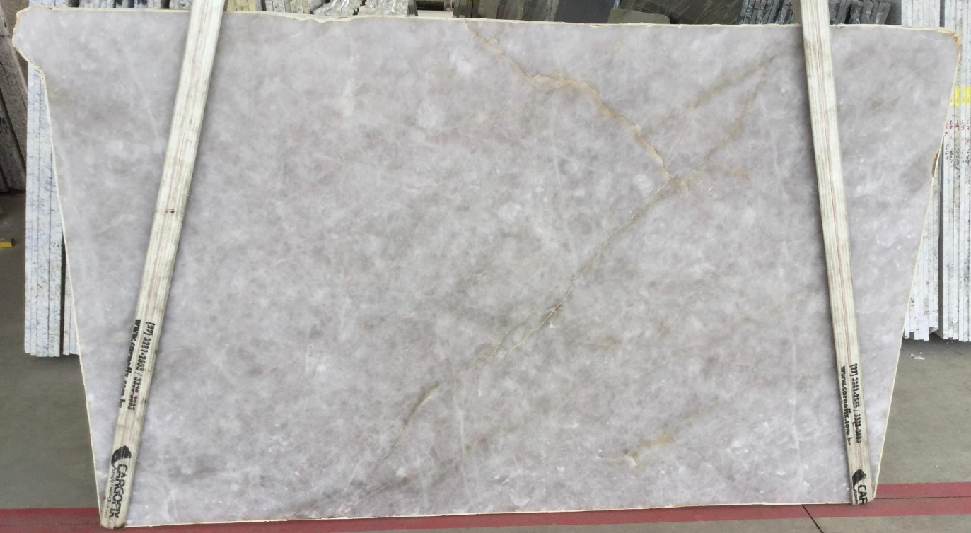 A large piece of marble is being lifted by a crane.