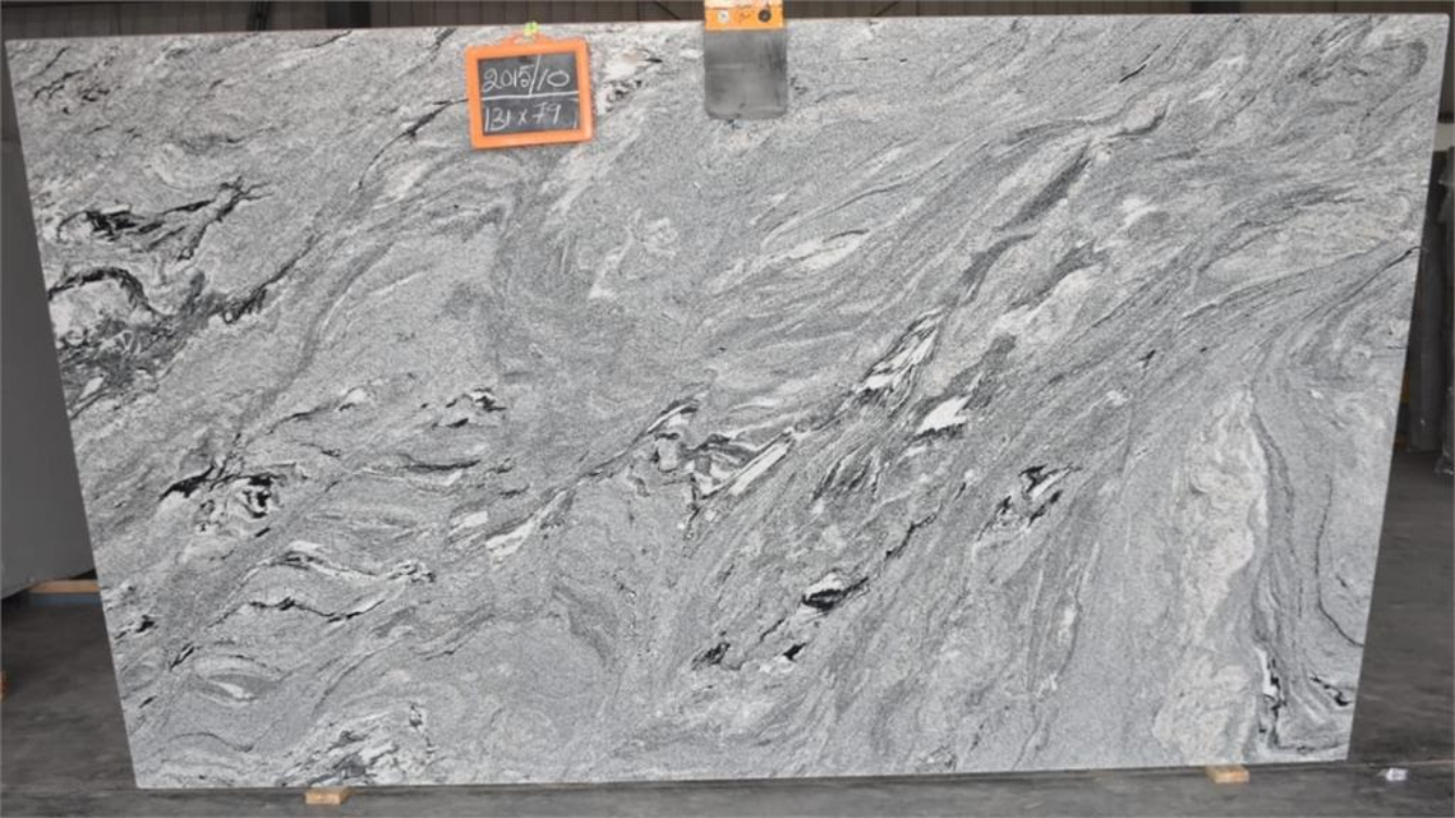 A large slab of gray granite is sitting on top of a cement floor.