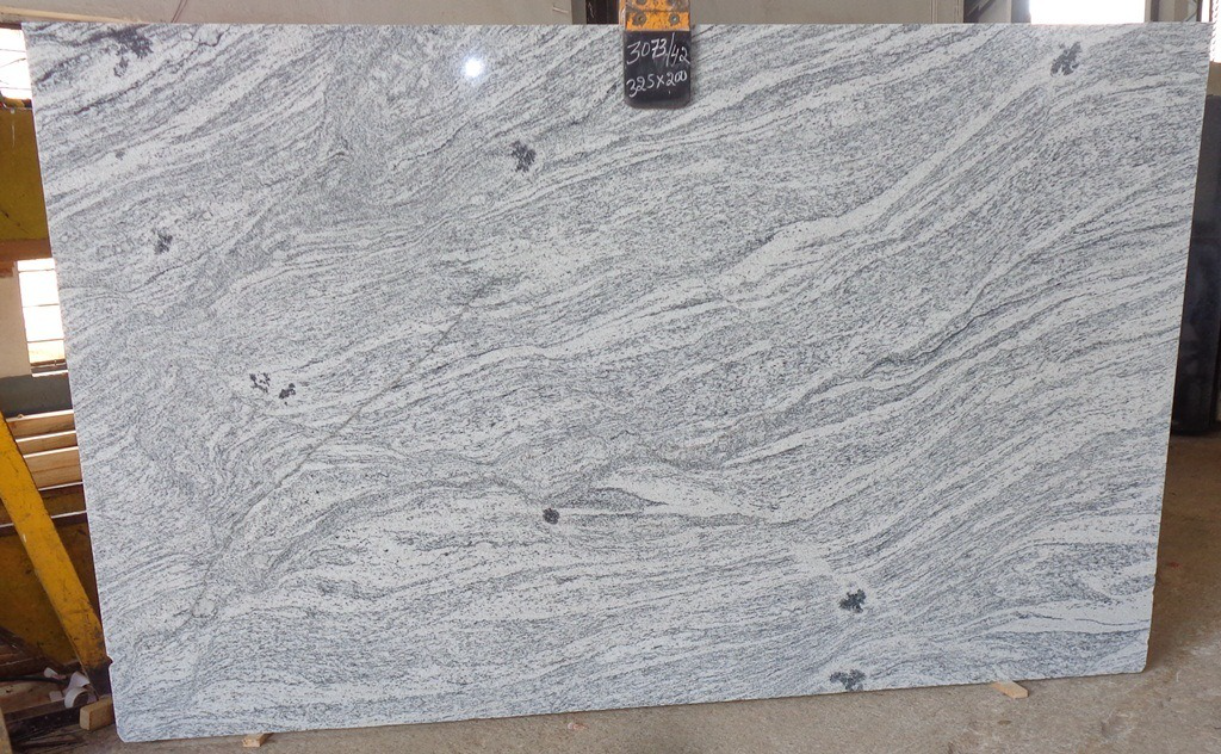 A large white granite slab is sitting on top of a concrete floor.