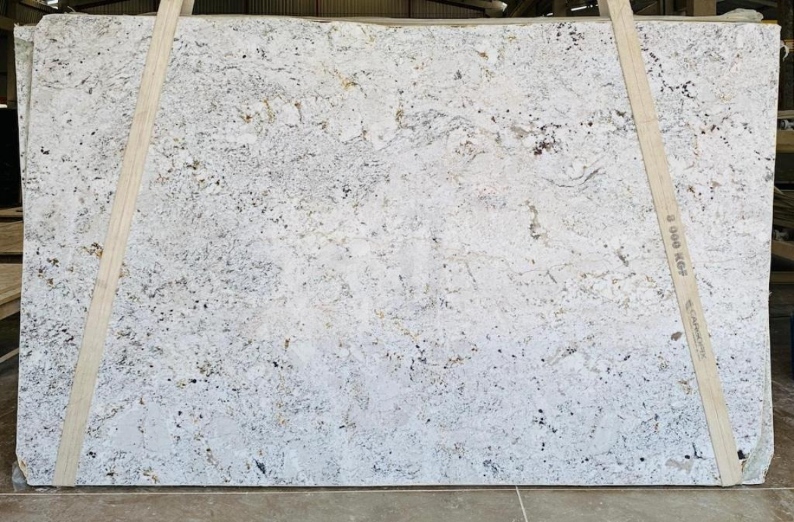 A large white granite slab is hanging from a wooden beam.