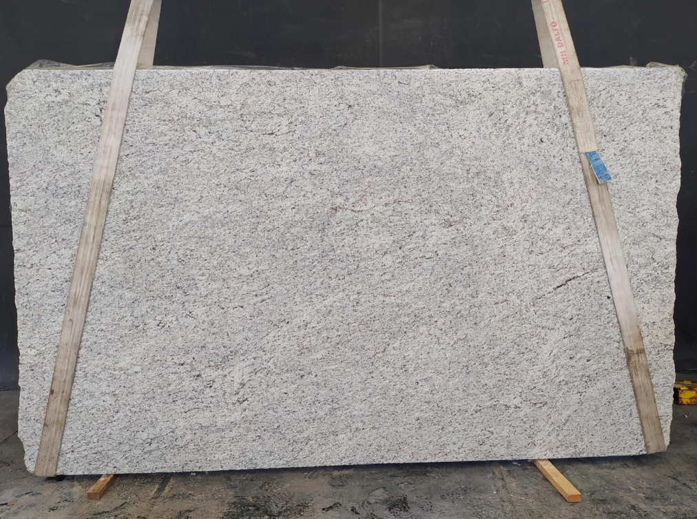 A large white granite slab is being displayed on a wooden stand.