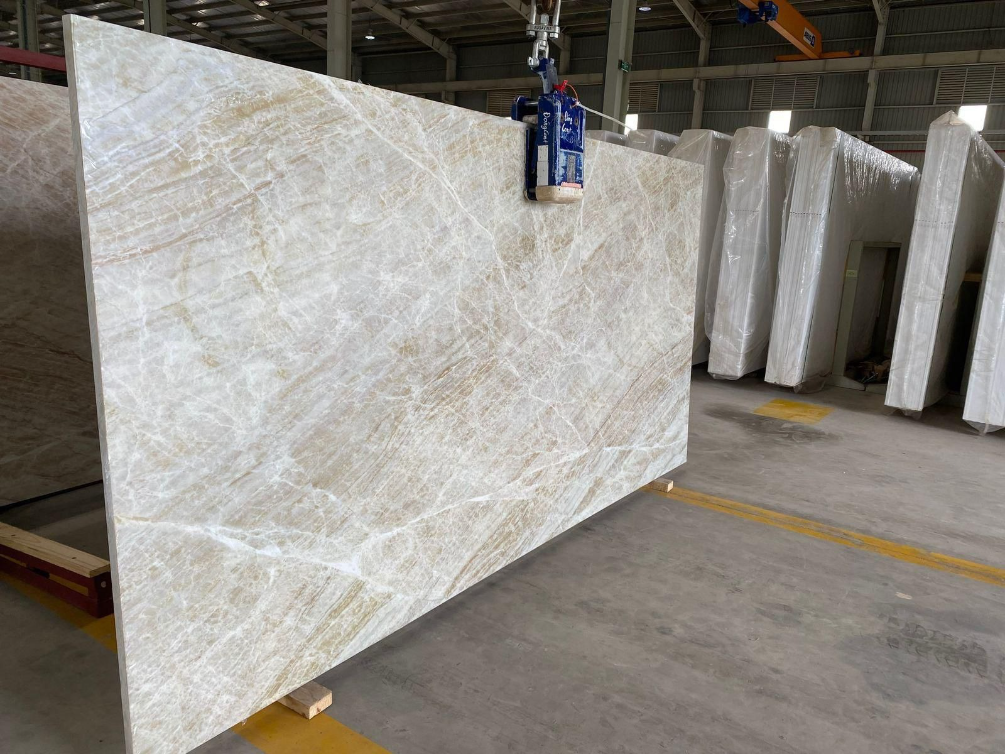 A large slab of marble is being lifted by a crane in a warehouse.