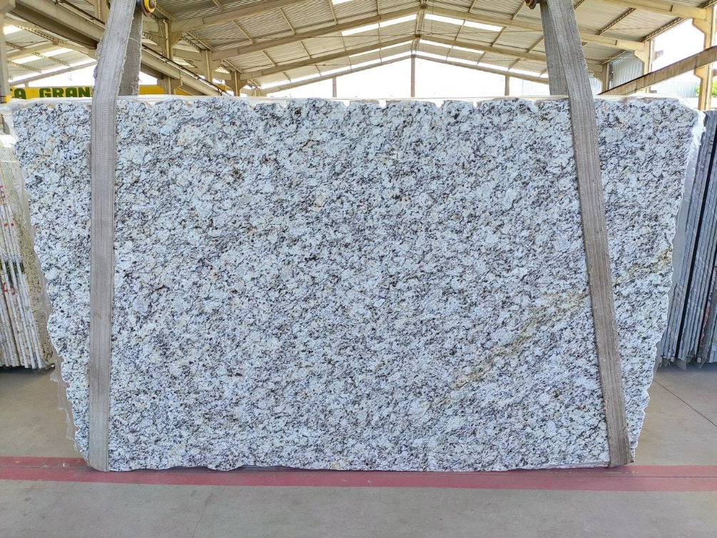 A large piece of granite is being lifted by a crane in a building.