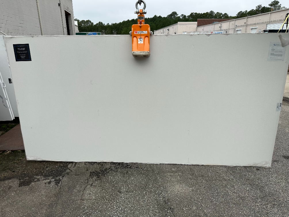 A large white slab of granite is being lifted by a crane.