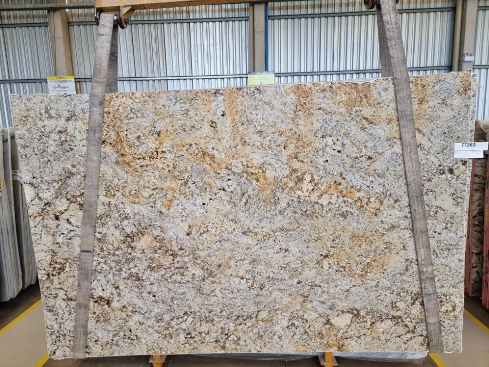 A large slab of granite is hanging from a rope in a warehouse.