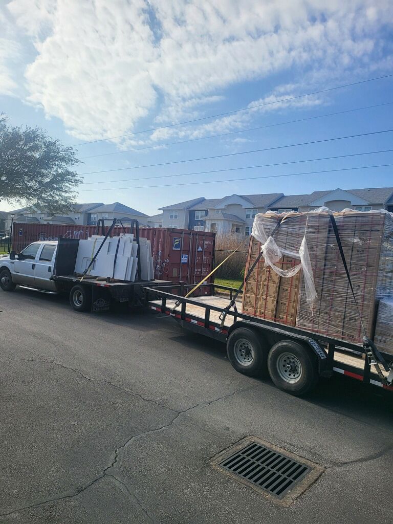 A truck is towing a trailer full of bricks down a street.