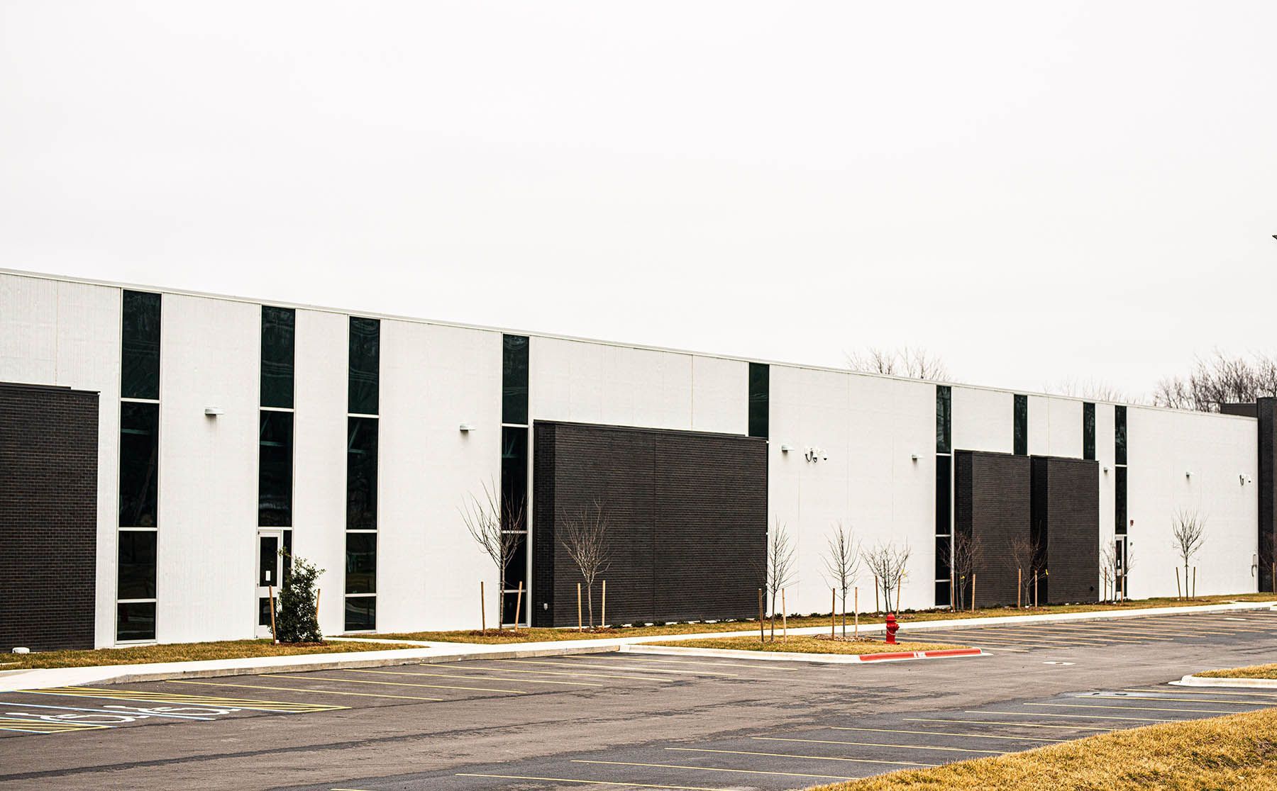A large white and black building with a parking lot in front of it.