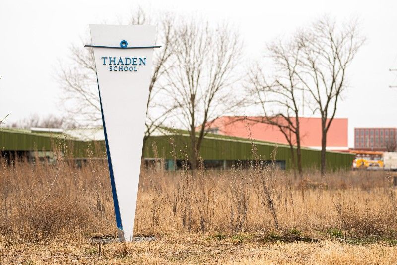 There is a sign in the middle of a field that says thaden school.