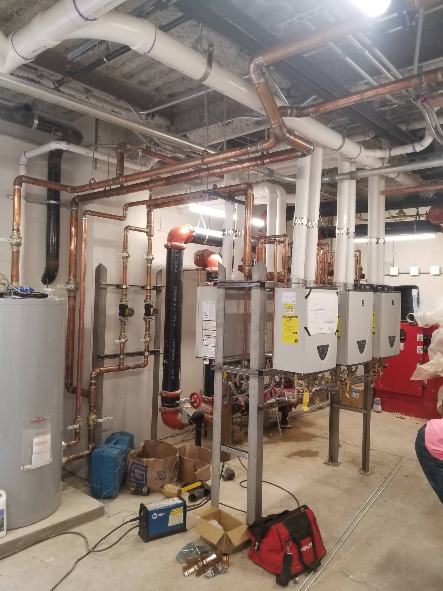 A room with a lot of pipes and a red bag on the floor.