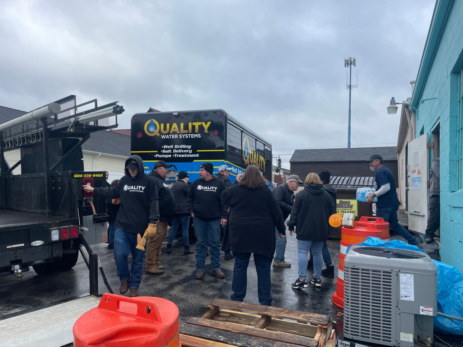 A group of people wearing dark jackets work near a bus labeled 
