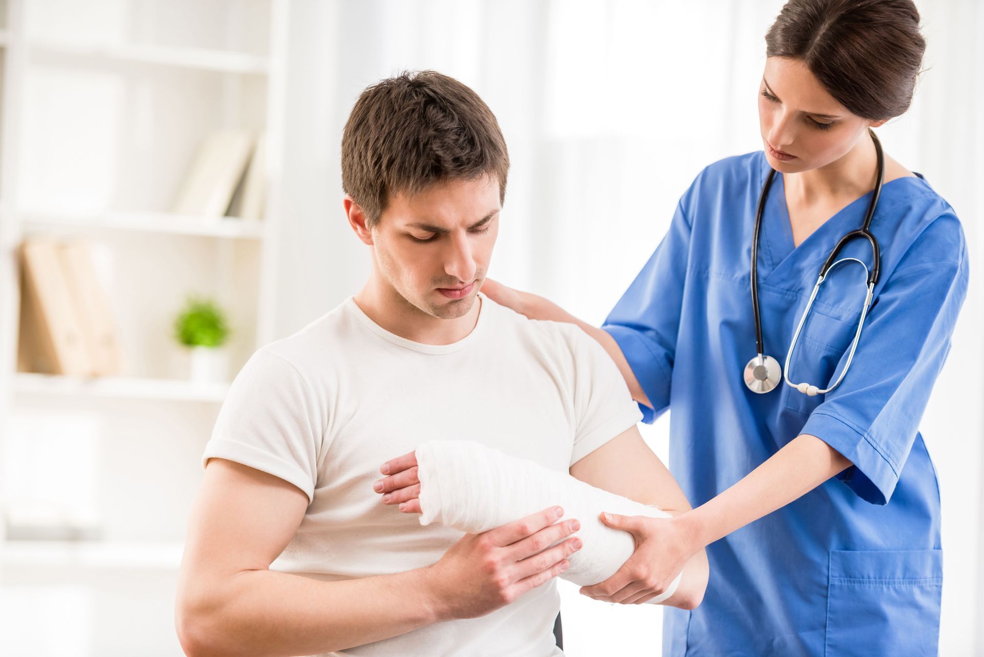A nurse consoling a man with a cast on his left arm.