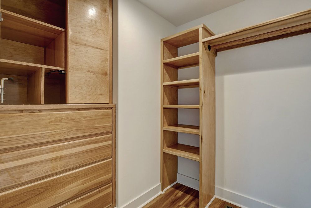 A walk in closet with wooden shelves and drawers.