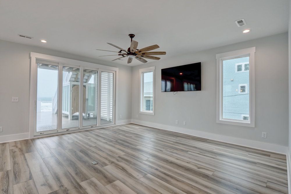 An empty living room with hardwood floors and a ceiling fan.