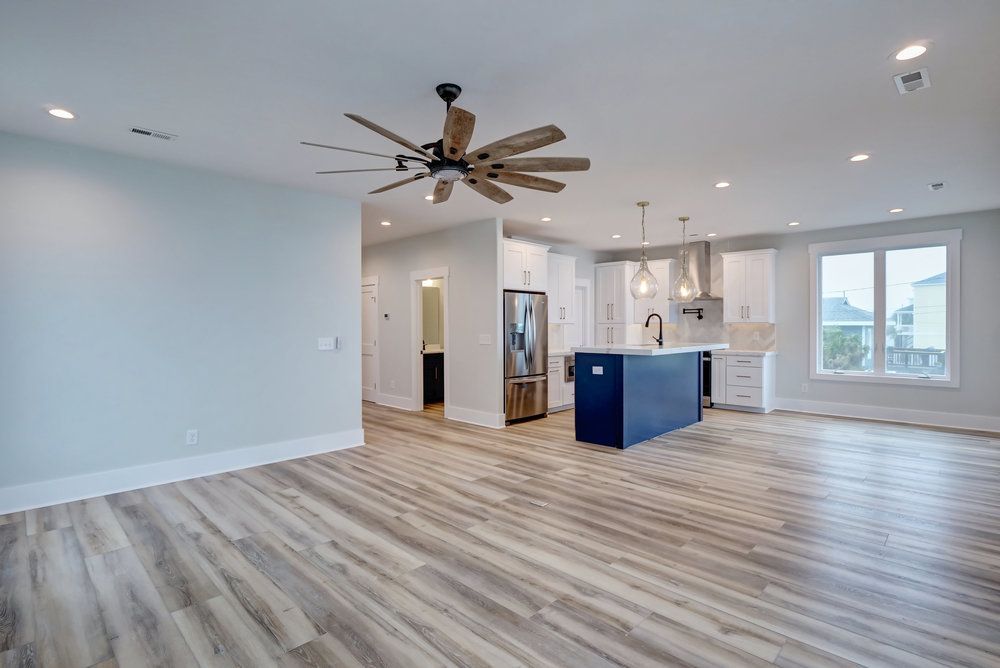 An empty living room with hardwood floors and a ceiling fan.