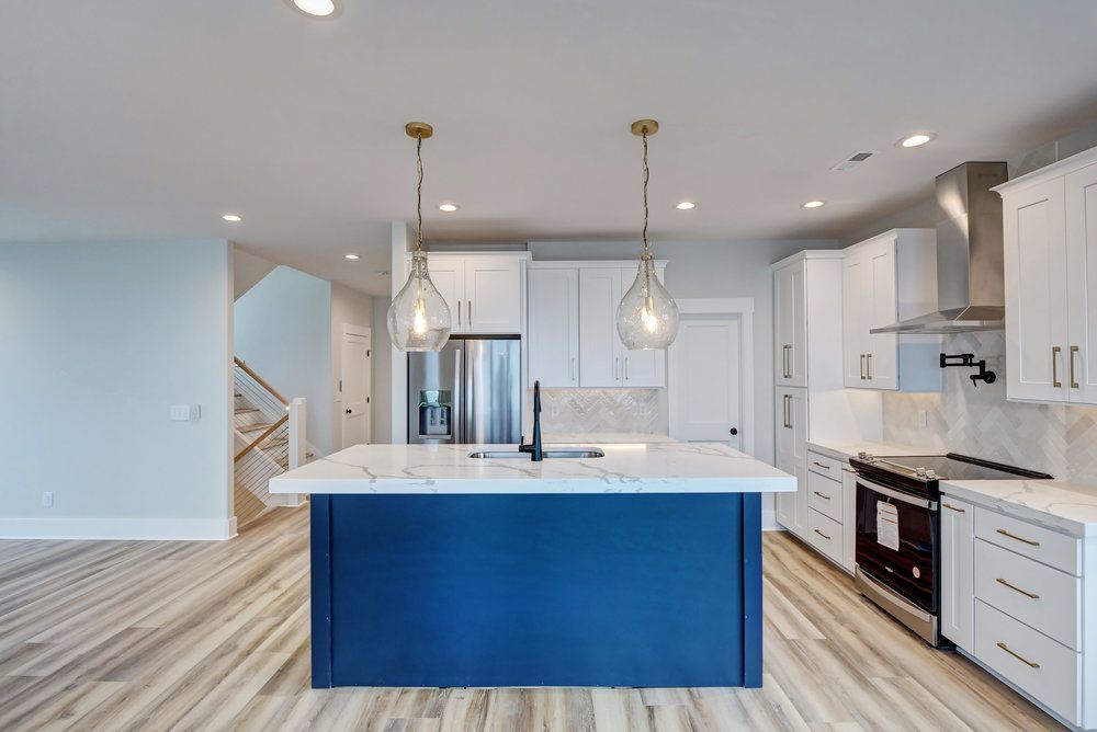A kitchen with white cabinets and a blue island in the middle.