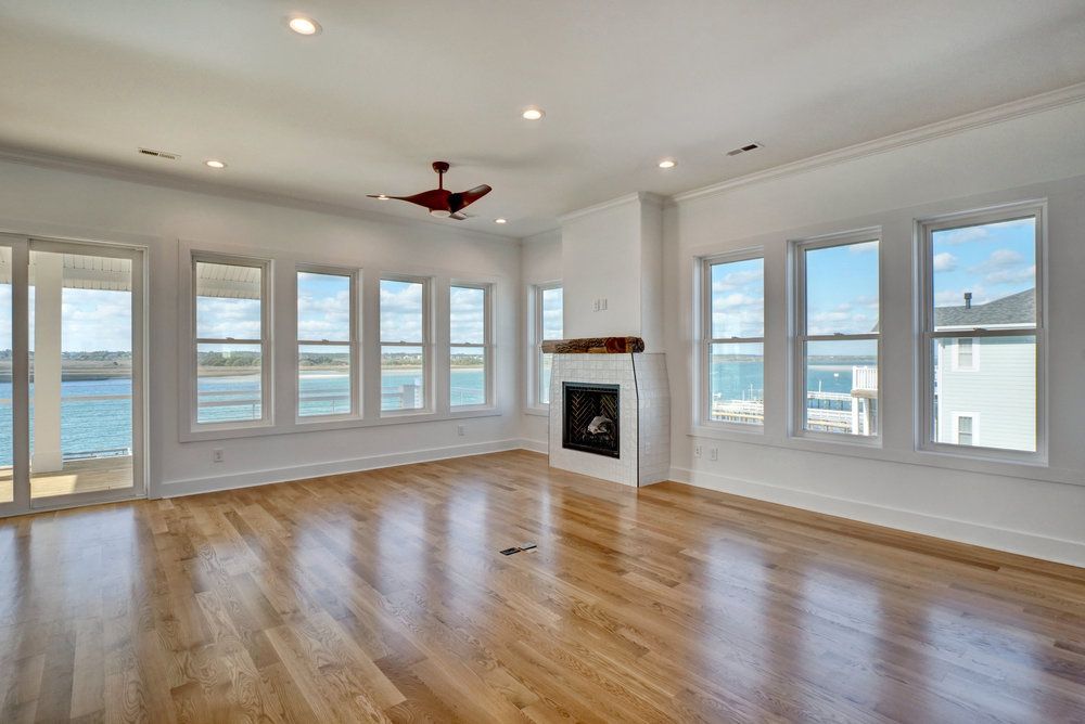 An empty living room with hardwood floors , a fireplace , and lots of windows.