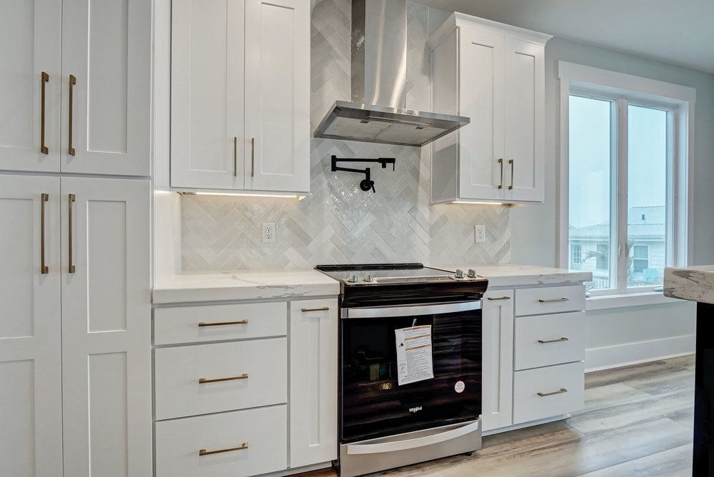 A kitchen with white cabinets , stainless steel appliances , and a stove.