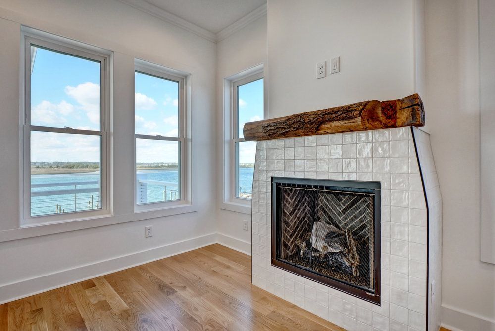 There is a fireplace in the middle of the room with a view of the water.