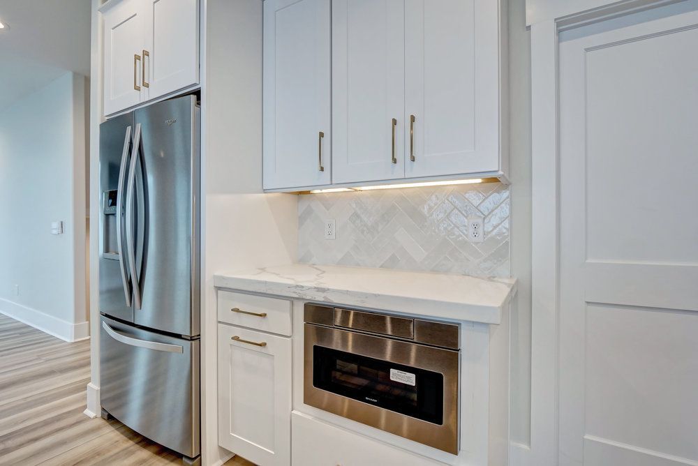 A kitchen with stainless steel appliances and white cabinets.