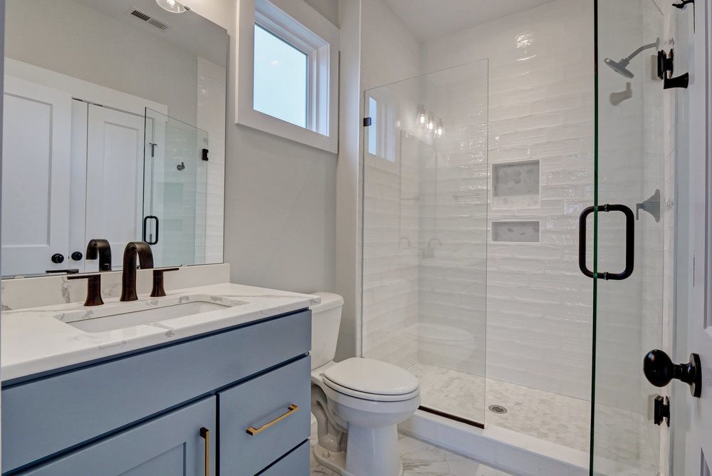 A bathroom with a toilet , sink , shower and mirror.