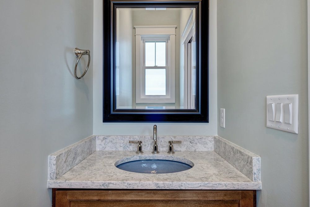 A bathroom with a sink , mirror and window.