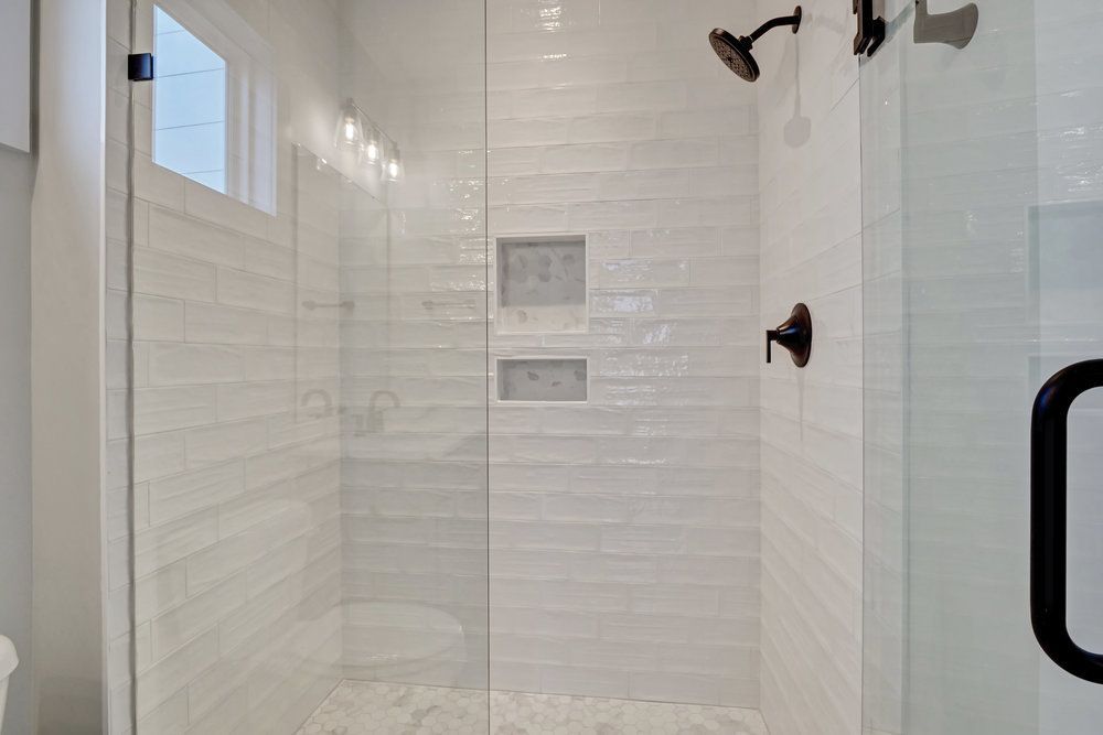 A bathroom with a walk in shower with a glass door.