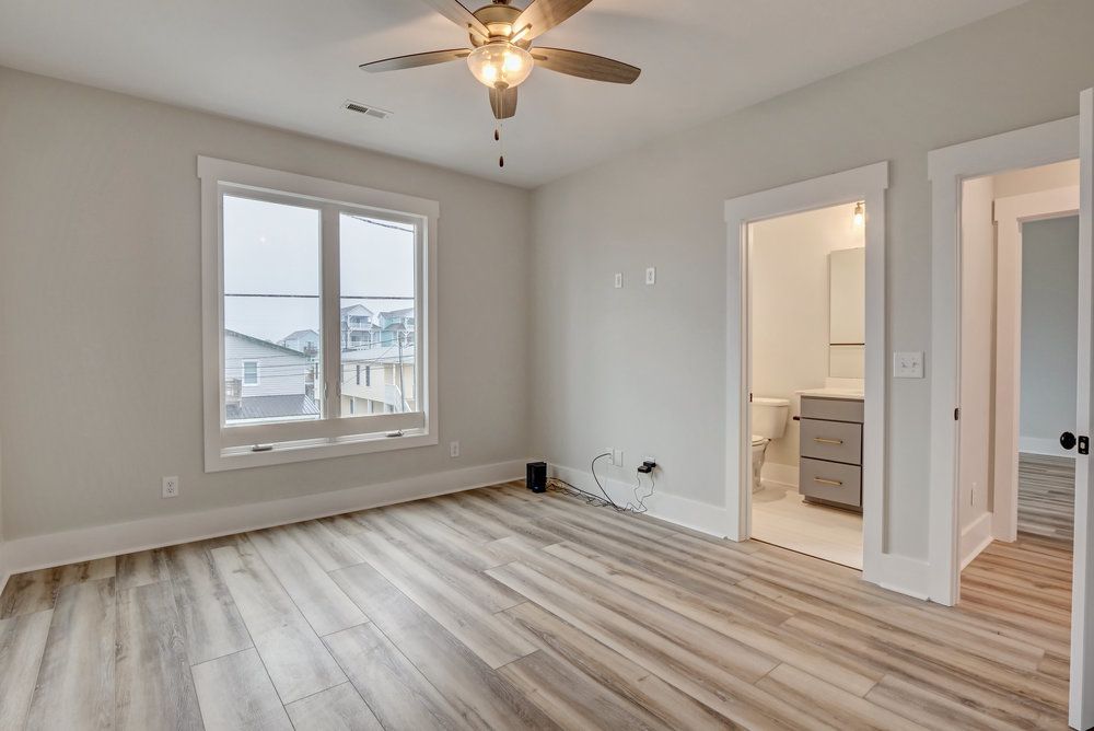An empty bedroom with hardwood floors and a ceiling fan.