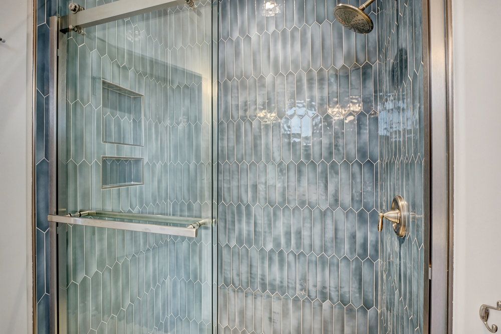 A bathroom with blue tiles and a sliding glass shower door.