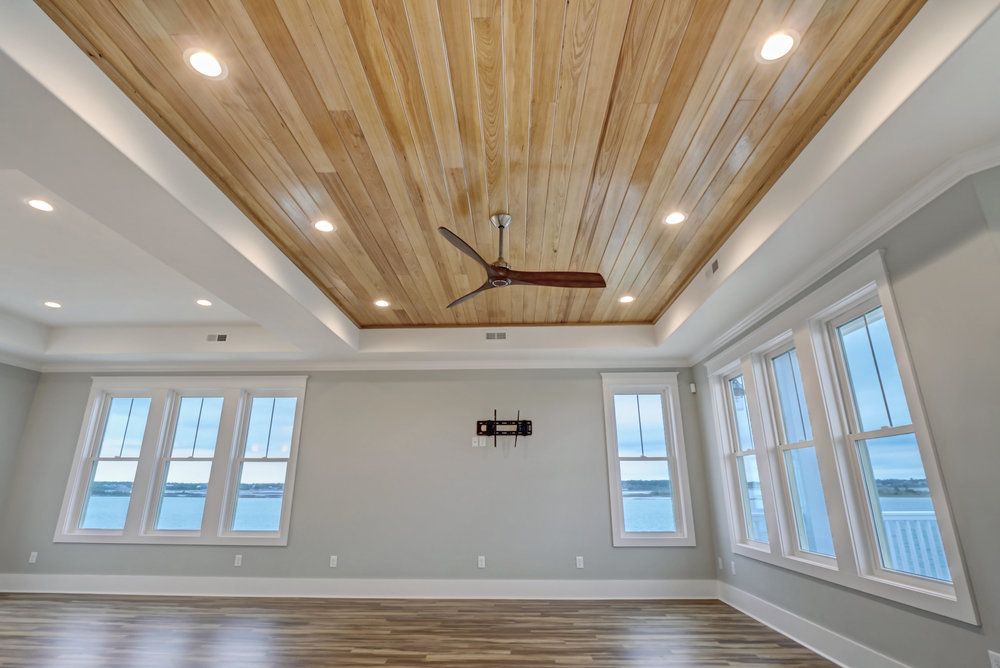 An empty room with a wooden ceiling and a ceiling fan