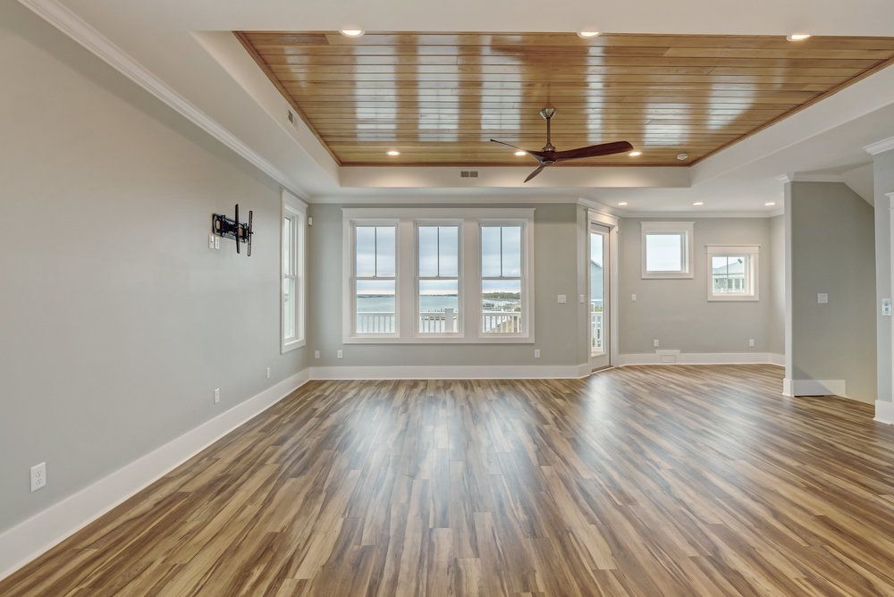 An empty living room with hardwood floors and a ceiling fan.