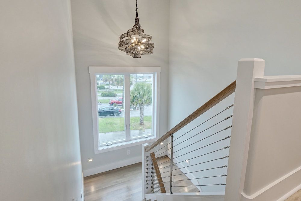 A staircase with a stainless steel railing and a chandelier hanging from the ceiling.