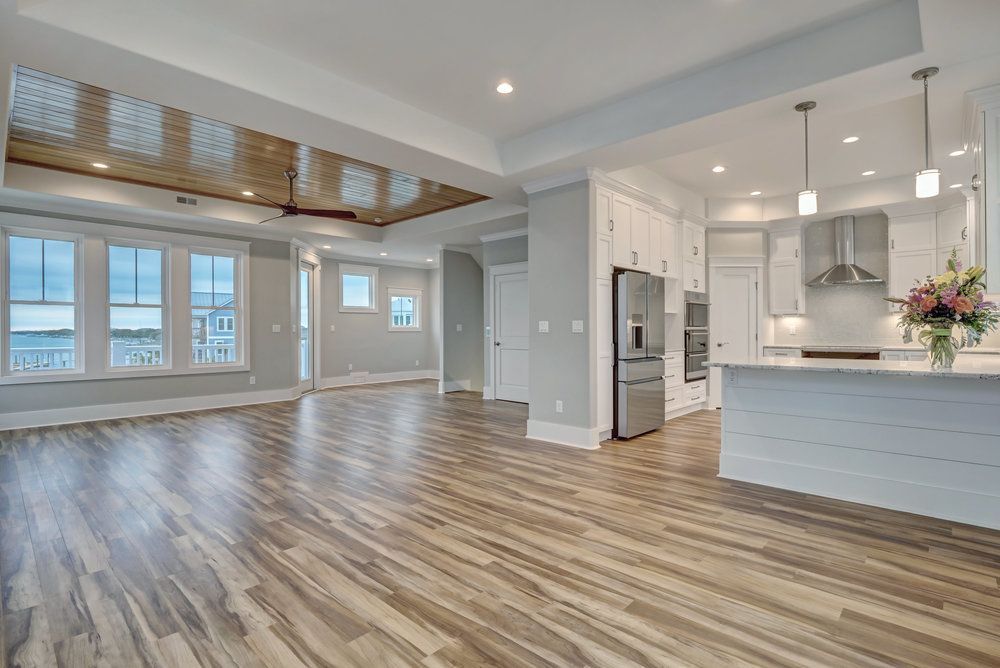 A large empty room with hardwood floors and a kitchen.