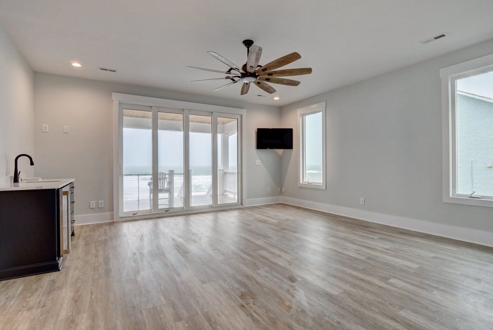 An empty living room with hardwood floors and a ceiling fan.