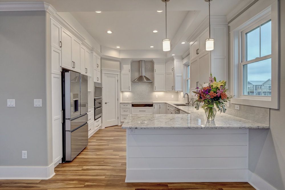 A kitchen with white cabinets and stainless steel appliances and a vase of flowers on the counter.