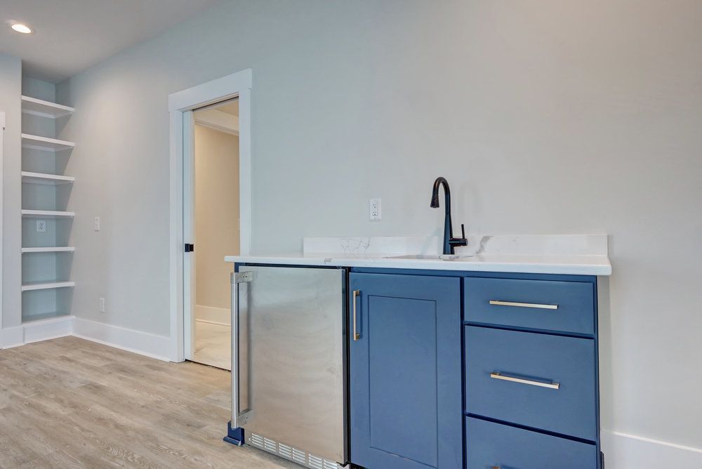 A kitchen with blue cabinets , a sink , and a refrigerator.