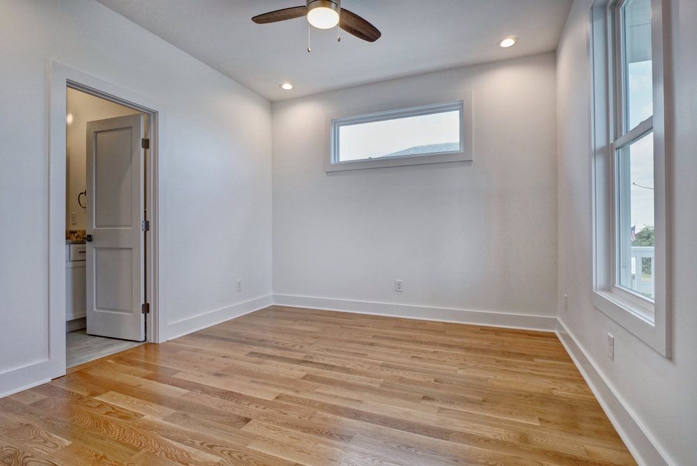 An empty bedroom with hardwood floors and a ceiling fan.