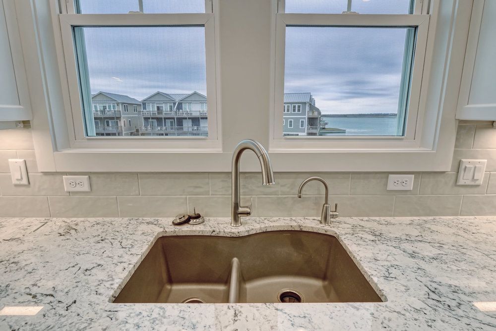 A kitchen sink with a view of the ocean and a window.