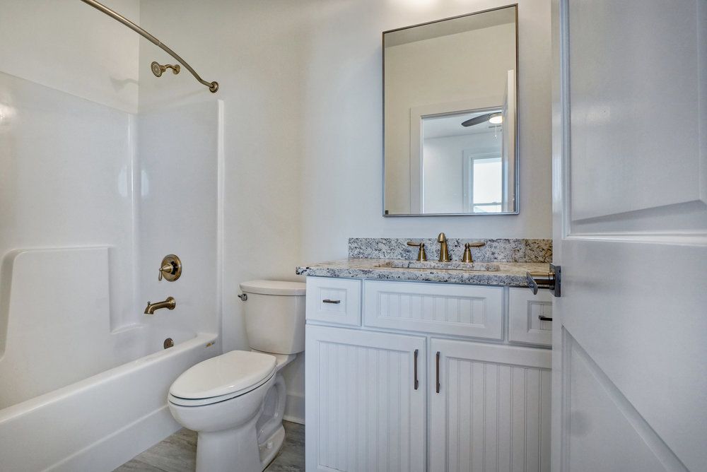A bathroom with a toilet , sink , bathtub and mirror.
