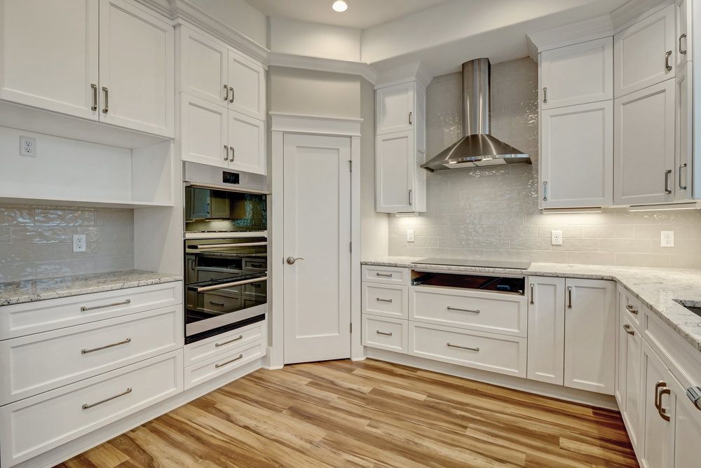 A kitchen with white cabinets , stainless steel appliances , and hardwood floors.