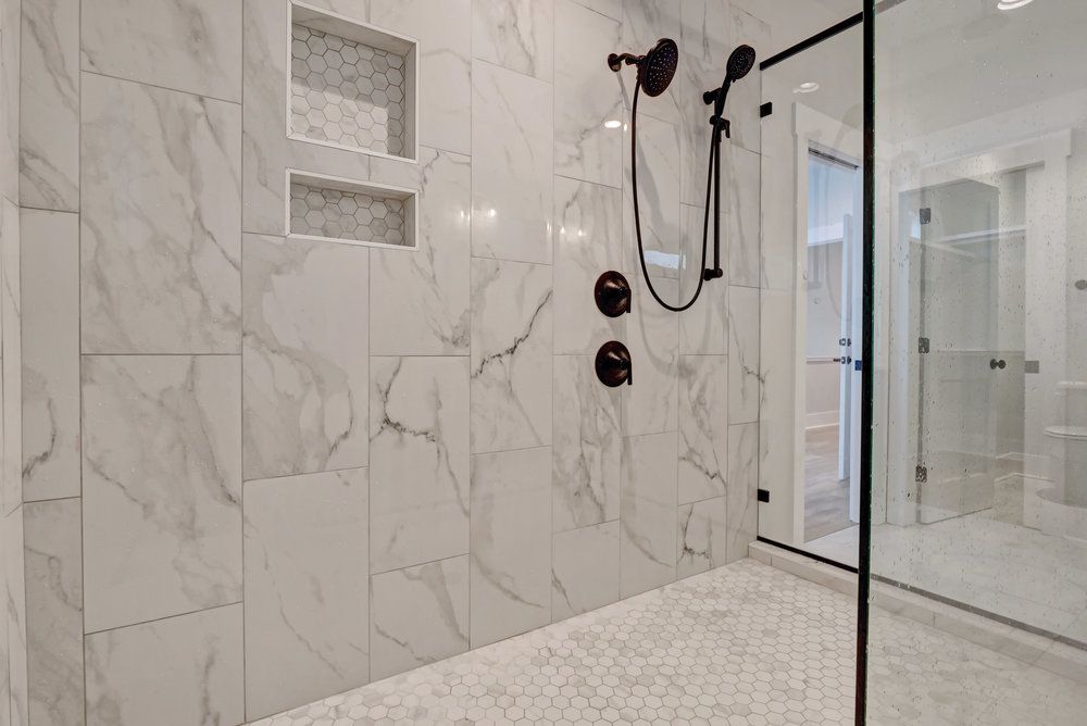 A bathroom with marble tiles and a walk in shower with a glass door.